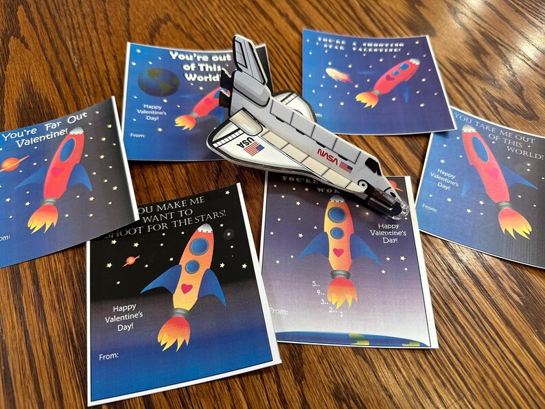 Puede incluir: Cinco tarjetas del D&iacute;a de San Valent&iacute;n con tem&aacute;tica espacial. Las tarjetas muestran cohetes, estrellas y el texto "You're Far Out Valentine!"  "You're out of This World"  "You Make Me Want To Shoot For The Stars!"  "You'll Wonder"  "You Take Me Out Of This World!"