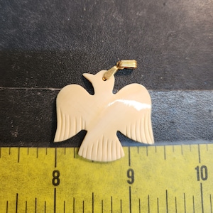 May include: A white carved bird pendant with a gold-tone chain. The bird is about 2 inches tall and has a detailed design.
