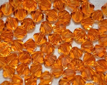 Puede incluir: Un montón grande de pequeñas cuentas de vidrio naranja facetadas. Las cuentas están dispuestas en un patrón aleatorio y todas son del mismo tamaño.