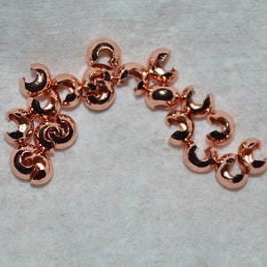 Puede incluir: Un grupo de cuentas de crimpado de oro rosa, utilizadas para la elaboración de joyas.