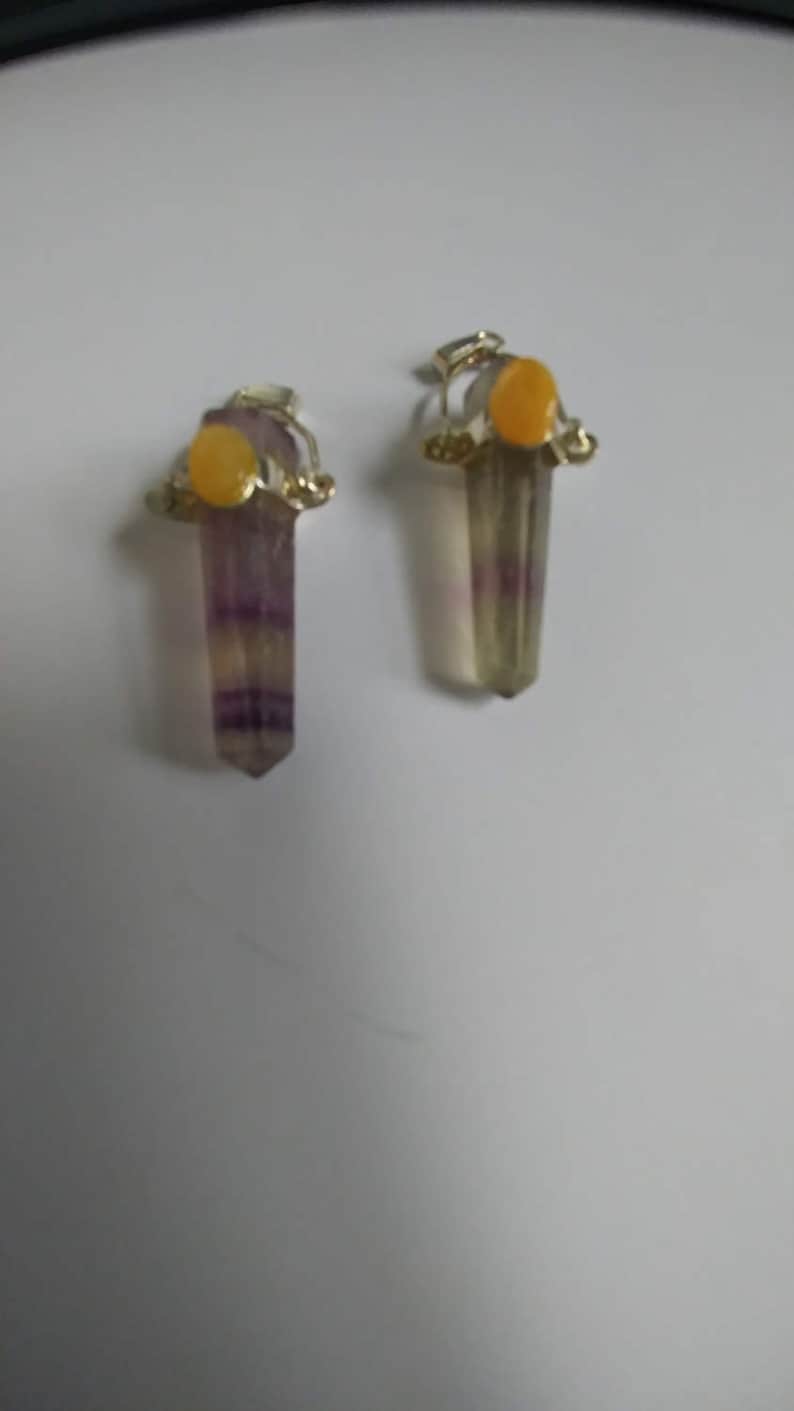 May include: A pair of earrings with purple and green fluorite crystal pendants and yellow gemstone accents.