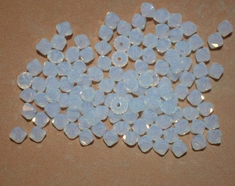 May include: A large group of white iridescent glass beads, with a faceted, teardrop shape.