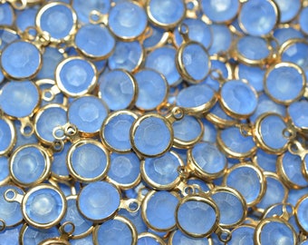 Puede incluir: Un gran grupo de cuentas de vidrio azul claro con detalles en metal dorado. Las cuentas tienen un diseño facetado y son perfectas para la elaboración de joyas.