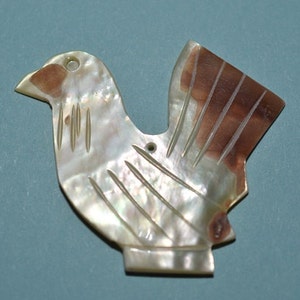 May include: A white and brown mother of pearl bird ornament with a hole for hanging.