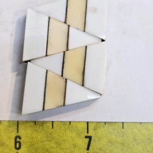 May include: A set of three white and cream triangular tiles with black lines. The tiles are arranged in a staggered pattern.