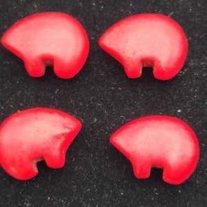 May include: Four red ceramic bear figurines. Each bear is standing on all fours and has a simple, stylized design.