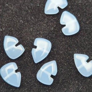 以下が含まれることがあります： 黒い表面に、矢印の形をした半透明の白いプラスチック製のギターピックが7つあります