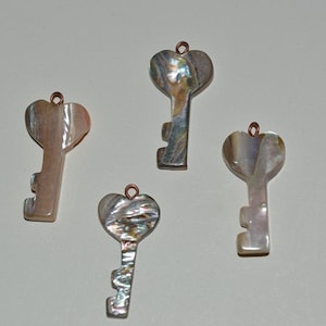 May include: Four iridescent key-shaped pendants with heart-shaped tops. The keys are made of mother of pearl and have a copper-colored loop at the top.