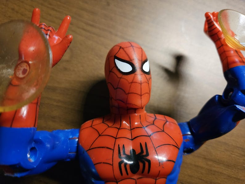 以下が含まれることがあります： 赤と青のコスチュームを着たスパイダーマンのアクションフィギュア。黒いクモのエンブレムとクモの巣のディテールが特徴です。フィギュアは白い目を持ち、透明な円形のウェブシューターを持っています。コレクションアイテムです。