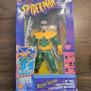 以下が含まれることがあります： デラックス版スパイダーマンのアクションフィギュア、ドクター・オクトパス付き。フィギュアの高さは25.4cmで、完全にポーズ可能で、アクセサリーが付属しています。パッケージには、「スパイダーマン」と「ドクター・オクトパス」の文字が入った紫と青の都市景観デザインが施されています。