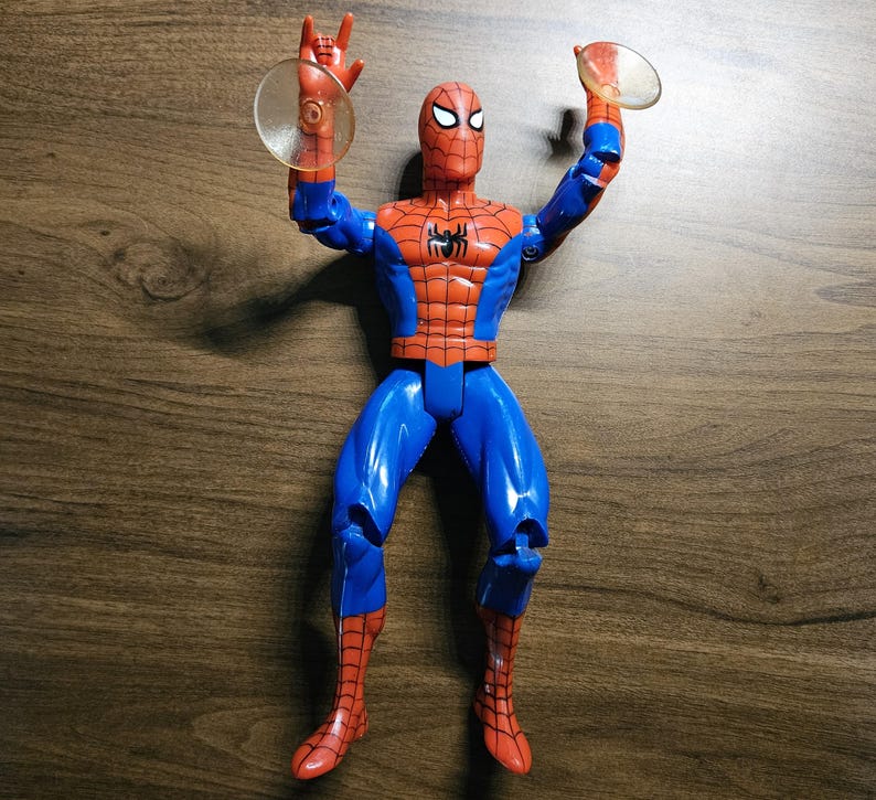 以下が含まれることがあります： ダイナミックなポーズの、赤と青のコスチュームを着たスパイダーマンのアクションフィギュア。ウェブシューター付き。胸にクモのエンブレムとマスクが付いた、詳細なデザインです。フィギュアの高さは約15cmです。