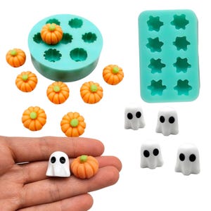 Op de afbeelding: Twee turquoise siliconen mallen voor knutselwerk, een ronde met pompoenvormige holtes en een rechthoekige met spookvormige holtes. Bevat diverse kleine oranje pompoenfiguurtjes en witte spookfiguurtjes met zwarte ogen.