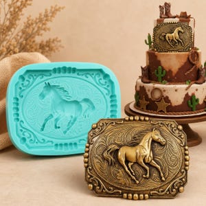 Puede incluir: Un molde de silicona turquesa y una hebilla de cinturón de metal dorado, ambos con un diseño de caballo corriendo. Un pastel de varios niveles con decoraciones temáticas de vaqueros está en el fondo.