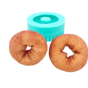 May include: Two small, round, brown donuts with a hole in the center. A turquoise silicone donut mold is also in the image.