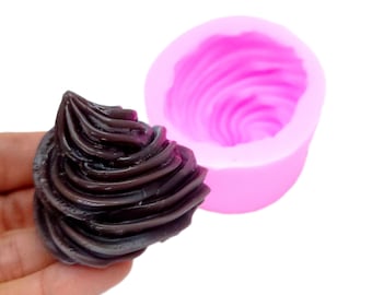 May include: A pink silicone mold for making chocolate swirls. The mold is shaped like a swirl and has a smooth, shiny finish. A dark chocolate swirl is shown next to the mold.