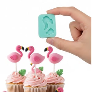 May include: Pink flamingo cupcake toppers with black beaks and yellow accents, atop cupcakes with pink frosting and green leaf decorations. A teal silicone mold with flamingo shapes is held in the background.
