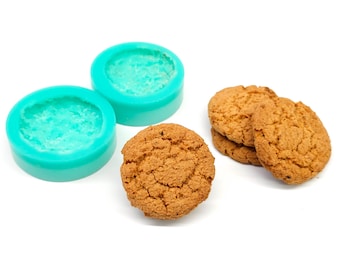 May include: Two turquoise silicone molds for baking cookies, and three round, golden brown cookies.