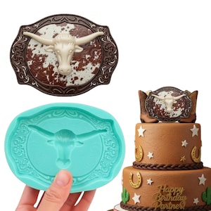 May include: A cake with a western theme, featuring a brown and white belt buckle design with a longhorn skull. A blue silicone mould of the same design is also shown. The cake has brown frosting with stars, horseshoes, and a cactus.