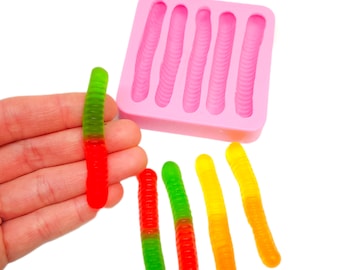 May include: Pink silicone mold with five cavities shaped like gummy worms. Five gummy worms are shown, two red and green, two yellow and green, and one yellow and orange.
