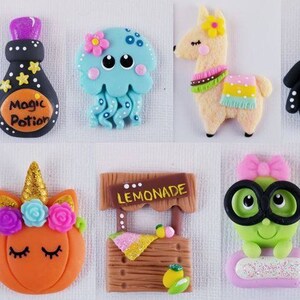 May include: A set of ten colorful polymer clay charms featuring various characters and objects, including a mermaid tail, a magic potion bottle, a jellyfish, a llama, a spider, a fox, a pumpkin with a unicorn horn, a lemonade stand, a frog wearing glasses, and a firework.