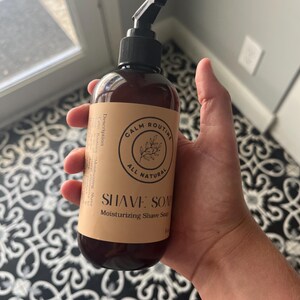 May include: A brown bottle of "SHAVE SOAP" with a black pump top, held in a hand. The label reads "CALM ROUTINE ALL NATURAL" and "Moisturizing Shave Soap". The bottle is approximately 5.5 inches tall.