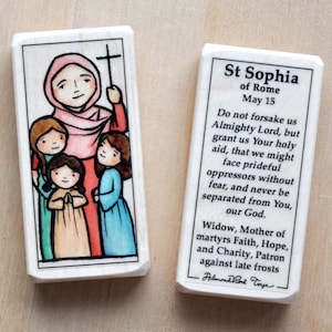 May include: A wooden prayer card with a colorful illustration of Saint Sophia of Rome, holding three children. The card includes a prayer to Saint Sophia, "Do not forsake us Almighty Lord, but grant us Your holy aid, that we might face prideful oppressors without fear, and never be separated from You, our God. Widow, Mother of martyrs Faith, Hope, and Charity, Patron against late frosts - Filmond Rod Toye"