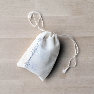 May include: A white cotton drawstring bag with the text "Almond Pearl Toys" written in black ink.