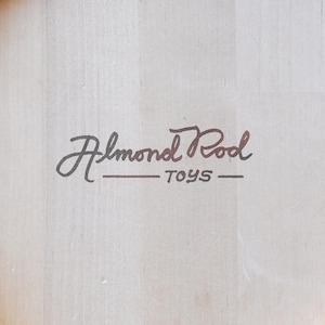 May include: A white wooden box with the text "Almond Pool Toys" in black and brown lettering.