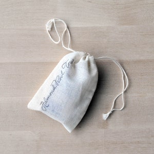 May include: A white cotton drawstring bag with the text "Almond Pearl Toys" written in black ink.