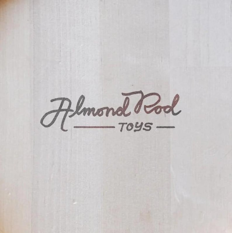 May include: A white wooden sign with black cursive writing that says "Almond Pool Toys".