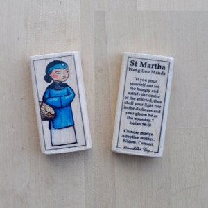 May include: A wooden block with a painted image of St. Martha, a Chinese martyr, holding a basket of fruit. The block also includes a quote from Isaiah 58:10 and a description of St. Martha's life.
