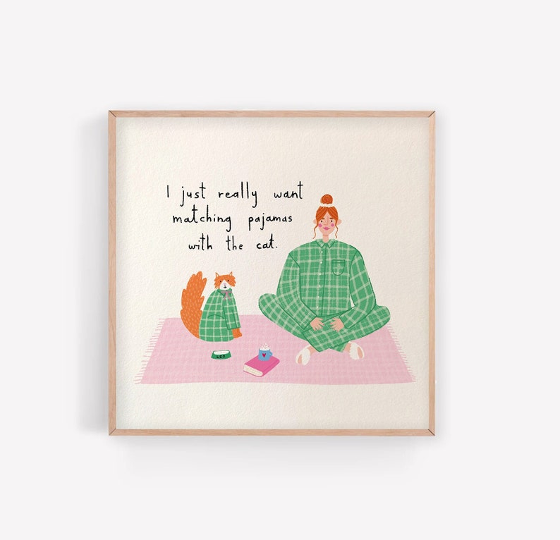 Image shows girl with ginger hair sitting crossed legged in her green check pyjamas. A fluffy ginger cat sits next to her in the same pyjamas. Text reads 'I just really want matching pyjamas with the cat'.