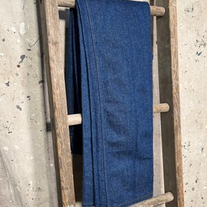 Puede incluir: Un par de pantalones vaqueros de color azul oscuro colgados de una escalera de madera.