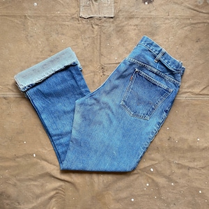 May include: A pair of blue denim jeans with a cuffed leg. The jeans have a classic straight leg style and are made of a durable denim fabric.