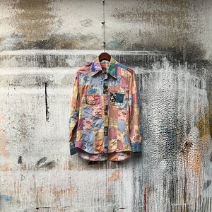 May include: A long-sleeved patchwork shirt with a button-up front and a variety of colours and patterns, including pink, blue, and brown.