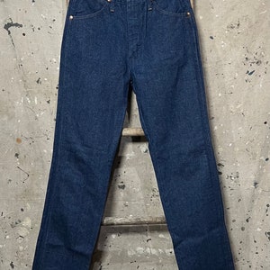 May include: A pair of dark blue denim jeans with a classic straight leg fit. The jeans have a button fly and belt loops.