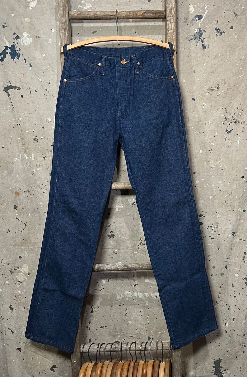 May include: A pair of dark blue denim jeans with a classic straight leg fit. The jeans have a button fly and belt loops.