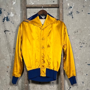 May include: A gold satin bomber jacket with a blue trim collar and cuffs. The jacket has a button closure and a relaxed fit.