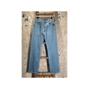 May include: A pair of light blue denim jeans featuring a classic five-pocket design, a button-fly closure, and a straight-leg cut. The denim has a faded wash with visible stitching along the seams and a standard waistband with belt loops.