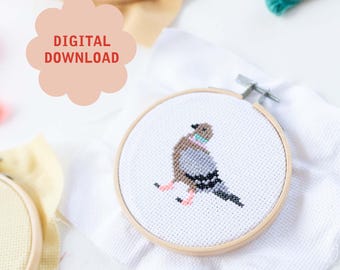 May include: A cross-stitch pattern of a dove with a pink collar, stitched on white Aida cloth and framed in a wooden embroidery hoop. The hoop is on a white surface with the text "DIGITAL DOWNLOAD" in red letters on a pink cloud.