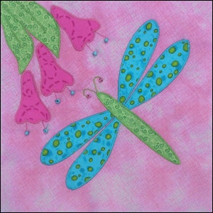May include: A blue and green dragonfly with polka dots on its wings is appliqued on a pink fabric background.  Pink flowers with green leaves are also appliqued on the fabric.