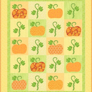 May include: A quilt block with a patchwork design featuring orange pumpkins with different patterns and green vines. The background is a light yellow with a green border.