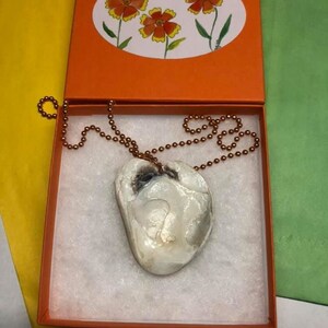 May include: A white iridescent shell pendant necklace with a copper chain in a small orange gift box. The box has a label with the text "Jennifer Heller Art and Jewelry,  Dogwoodanddesign.com".