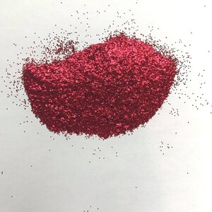 May include: A pile of red glitter on a white background.