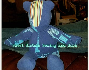 Pode incluir: Um urso de peluche de tecido azul e branco listrado com o texto "Sweet Sisters Sewing and Such" na frente.
