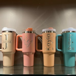 Row of colorful engraved tumblers — assorted examples showcasing name and design variations in multiple colors.