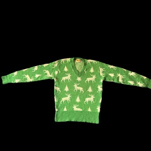 May include: A green sweater with a white reindeer pattern. The sweater has a V-neck and long sleeves.