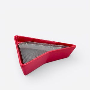 May include: A red, triangular tray with a mesh insert. The tray has a glossy finish and a modern design. The mesh insert is a dark gray color. The tray is empty and sits on a white background.