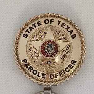 May include: Gold-colored metal keychain with a round badge featuring the words "STATE OF TEXAS PAROLE OFFICER" and a five-pointed star with a smaller star inside. The keychain has a silver metal ring.