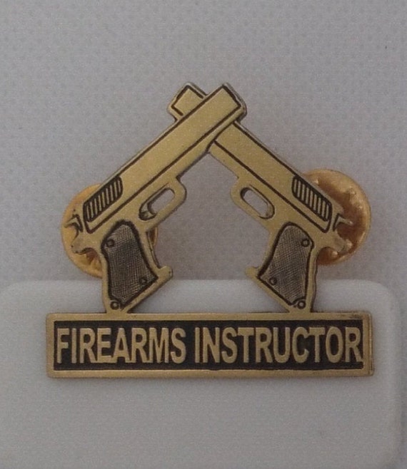 Handcrafted shirt or hat pin. featuring 2 firearms crossed at the tip of barrel written "FIREARMS INSTRUCTOR".
